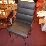 An Eames style high back chair upholstered in black leather and raised on chromed swivel supports