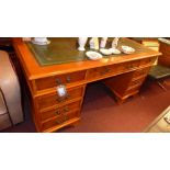 A yew wood pedestal desk the lined top above arrangement of drawers with metal handles