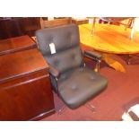 An Eames style high back office chair upholstered in black leather and raised on chromed swivel