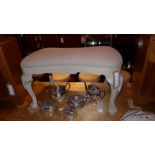 A painted distressed finish hearth stool of waisted form and upholstered in grey linen and raised on