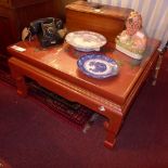 A Chinese red lacquered low table having exotic bird detail in relief and inset glass top