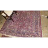 A Persian design carpet having red and navy fields with all over foliate decoration
