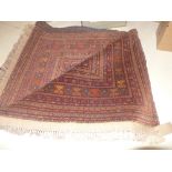 A hand knotted Afghan carpet the deep red fields with repeating flowerhead motifs in a white bored