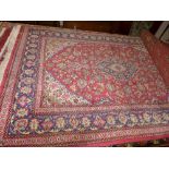 A hand knotted Persian rug the red fields with foliate decoration