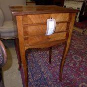 A French king wood bedside table with three single drawers on splayed supports