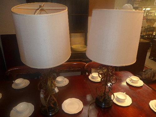 A pair of ornate wrought iron lamps and matching shades