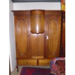 An early 20th Century mahogany two door wardrobe with oval panel doors above two base drawers on