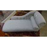 A chaise longue upholstered in grey fabric on castors