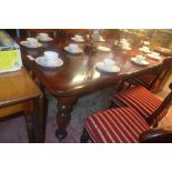 A Victorian mahogany extending dining table with two leaves on turning supports