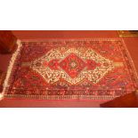 A hand knotted Persian rug the rouge field having geometric diamond lozenge and motifs in a triple