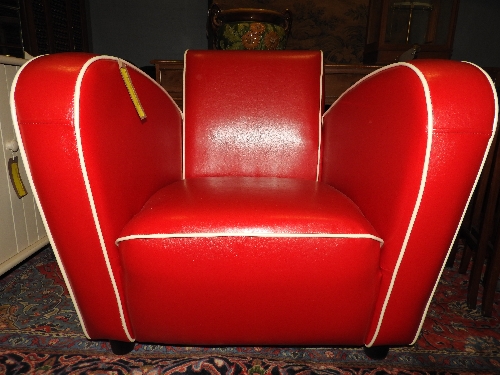 A contemporary Jean Renoir design red faux leather armchair of angular form with ivory piped detail