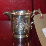 A Victorian hallmarked silver jug with embossed decoration and scrolling handle