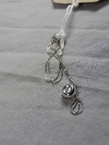 A 18ct white gold doughnut form pendant set single diamond on a fine link chain