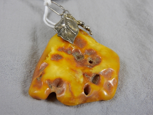 A 20th Century Oriental white metal mounted amber pendant (approx 16grams)