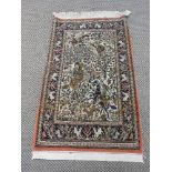 A hand knotted woolen and silk Qum rug the biscuit fields with hunting scene decorated centre