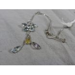 A 14ct white gold flower form pendant inset multicoloured stones on a fine link chain.