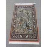 A hand knotted woollen and silk Qum rug the biscuit fields with hunting scene decorated centre