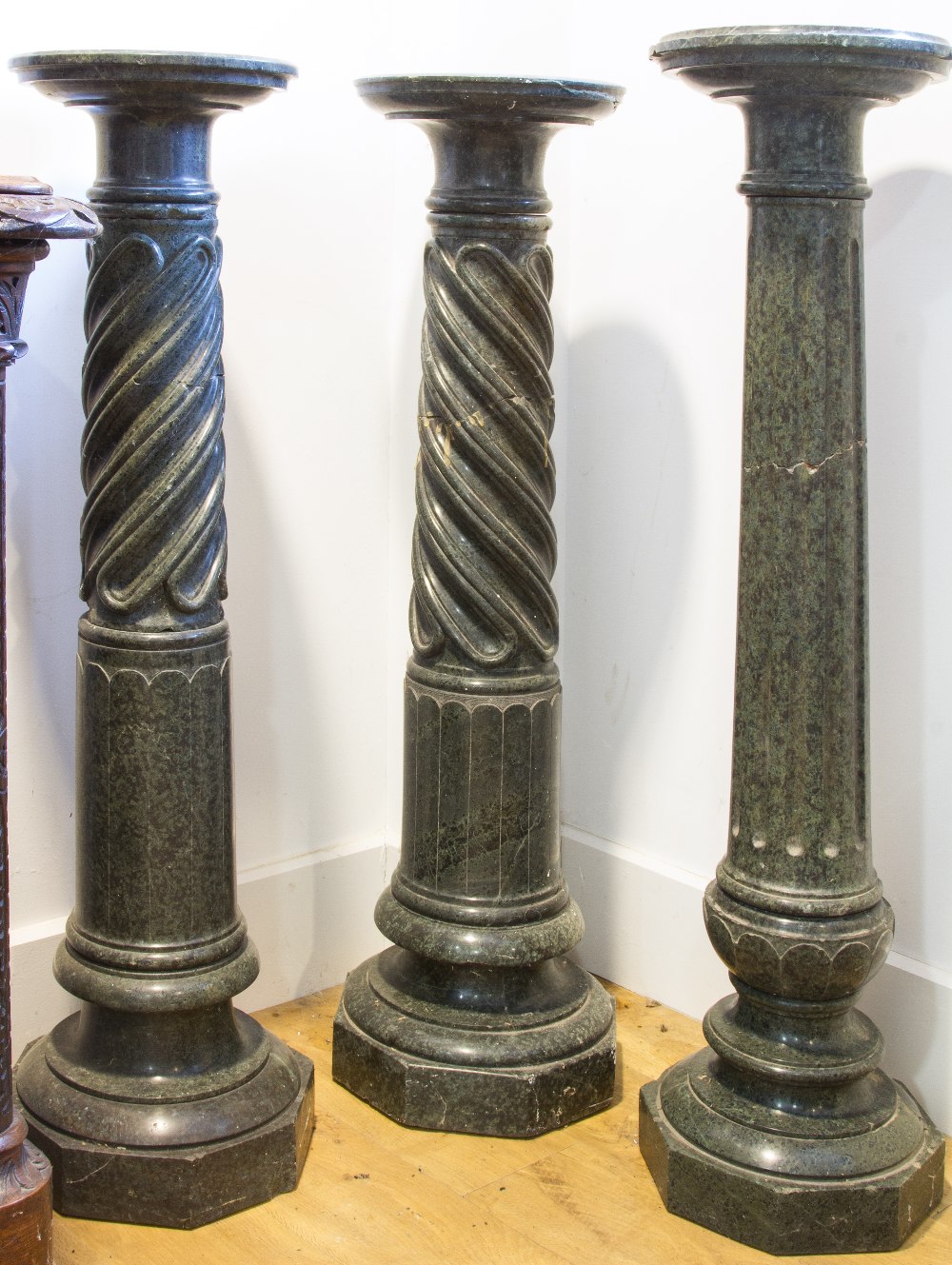 A NEAR PAIR OF 19TH CENTURY DARK GREEN MARBLE COLUMNS, each with a circular stand above twist and