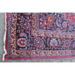 A LARGE EASTERN WOOLLEN RUG, predominantly red ground, central floral cartouche, 325 x 255 cm A/F