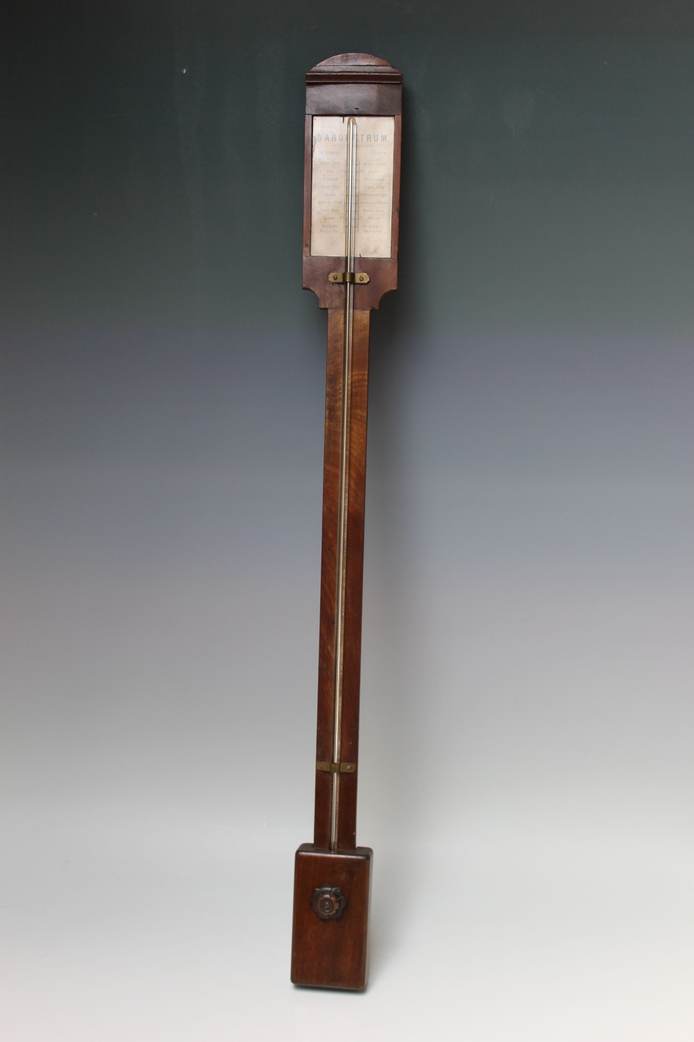 A DUTCH MAHOGANY STICK BAROMETER, the arched top above a paper scale, rectangular cistern cover with