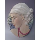 A BESWICK ART DECO WALL PLAQUE MODELLED IN LOW RELIEF OF A LADY IN PROFILE, flanked by flowers in