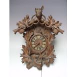 A BLACK FOREST CUCKOO CLOCK, the case with oak leaf and hunting themed carved decoration, stags head