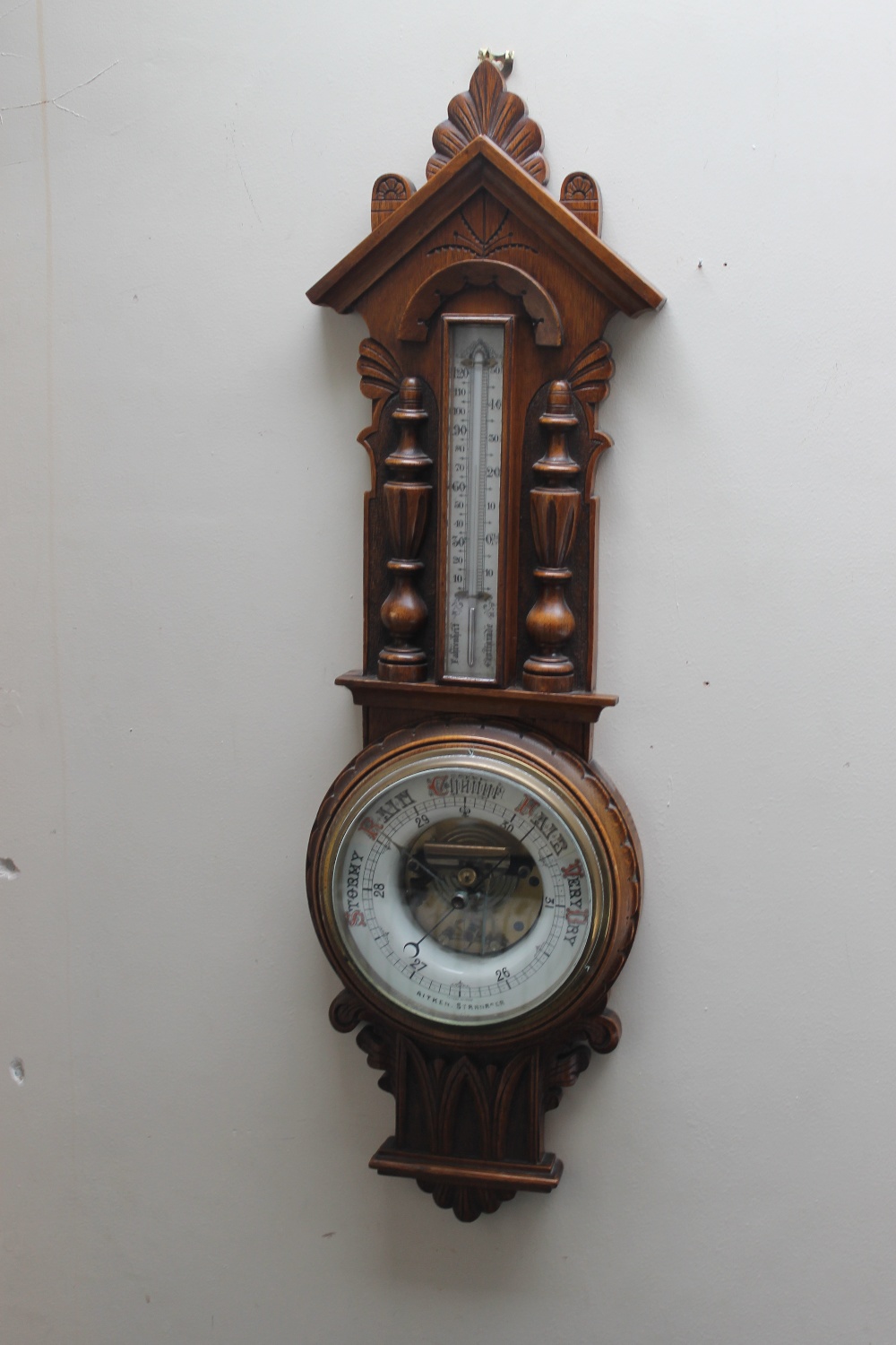 AN EARLY 20TH CENTURY OAK CARVED ANEROID BAROMETER, of Gothic style, carved with half turned