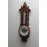 AN EARLY 20TH CENTURY OAK CARVED ANEROID BAROMETER, of Gothic style, carved with half turned