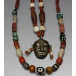 Zwei Halsketten.a) Mit Bronzemaske als Symbol einer Kopftrophäe mit Spiralornamenten auf den