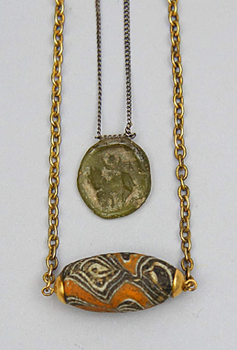 Antikes Glasmedaillon und -perle.Grünlich-gelbes Glasmedaillon mit Darstellung einer weiblichen