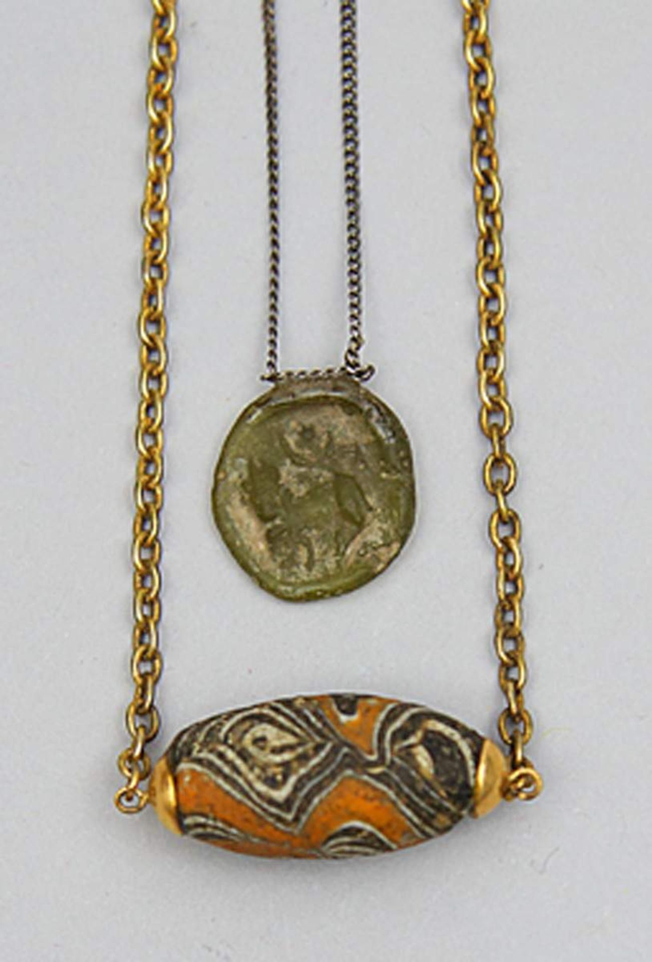 Antikes Glasmedaillon und -perle.Grünlich-gelbes Glasmedaillon mit Darstellung einer weiblichen