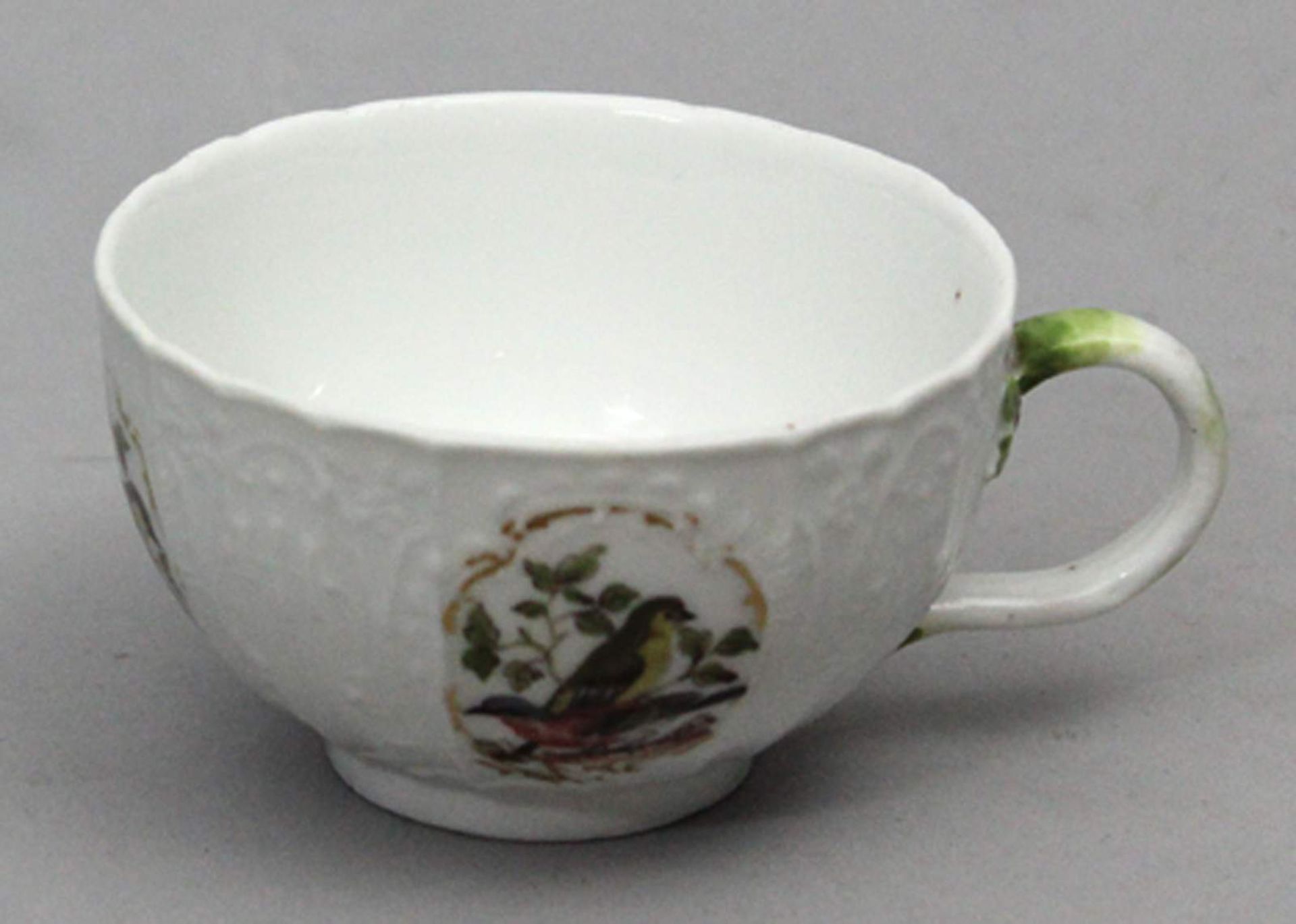 Tasse, Meissen.Halbkugelig mit Asthenkel und reichem Reliefdekor. In vier umlaufenden Reserven