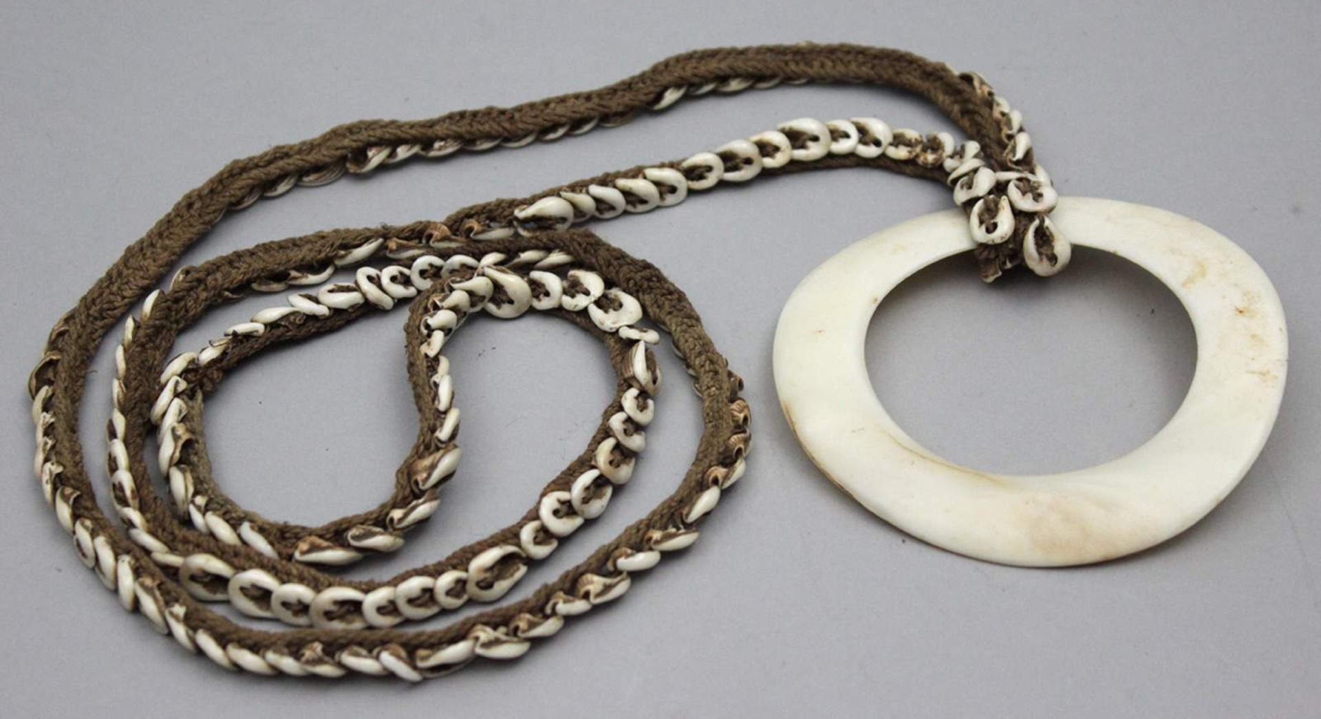 Halskette mit Tridacna-Ring, Melanesien/Papua-Neuguinea.Mit Nassa-Schnecken besetztes Band aus