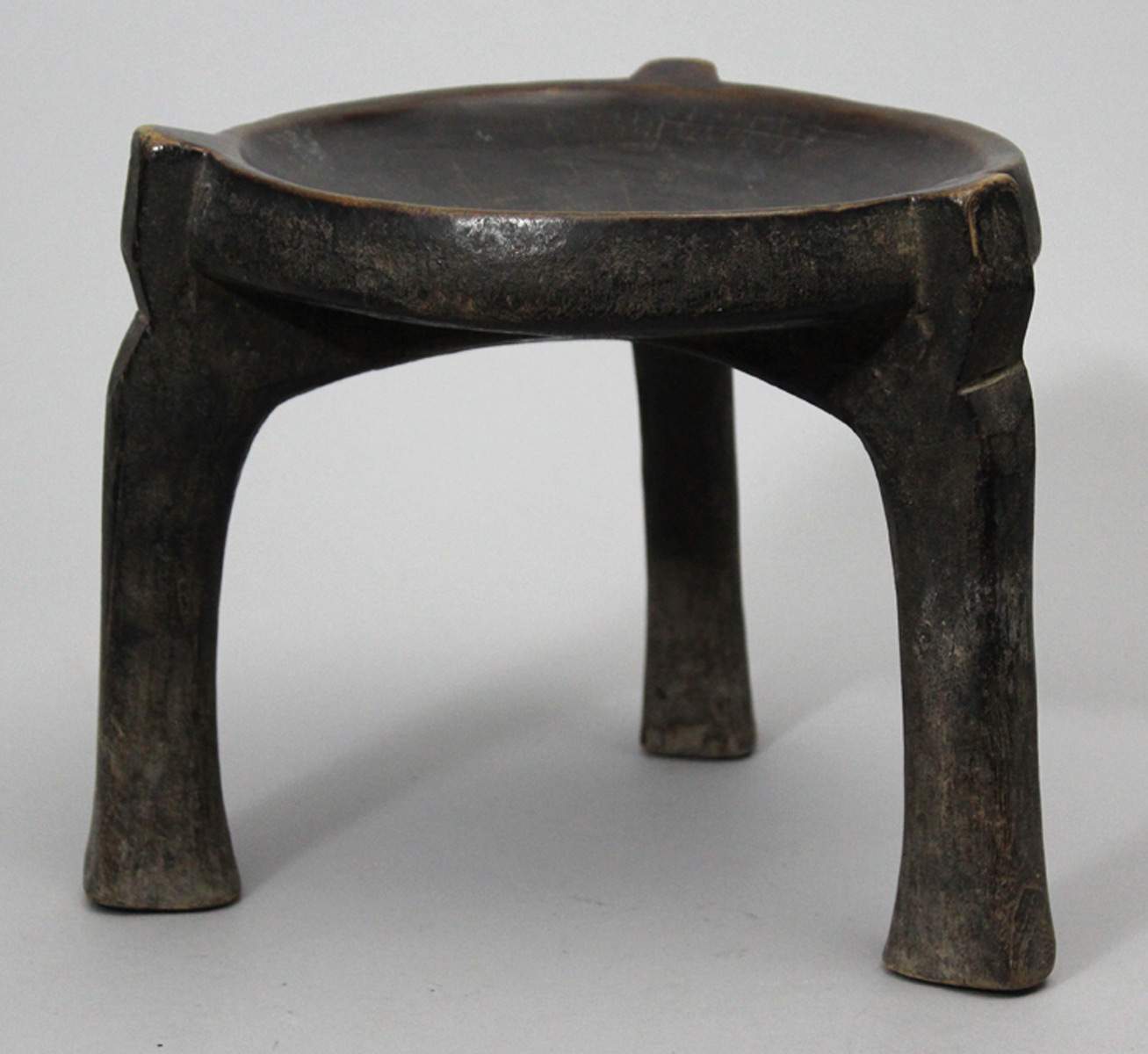 Hocker, Hehe.Holz. Sitzfläche mit dunkler Gebrauchspatina. Niedrige Form auf drei leicht