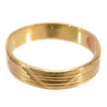 A gold coloured band ring, with reeded decoration, finger size M 1/2  A gold coloured band ring,