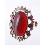 A garnet and diamond ring, the central oval cabochon garnet in a collet setting  A garnet and