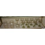 A set of nine hock glasses, with clear glass bowls and green stems, the bowls etched with fruiting