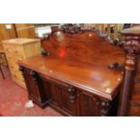A Victorian mahogany pedestal sideboard, the arched rear gallery decorated with scroll motifs, the