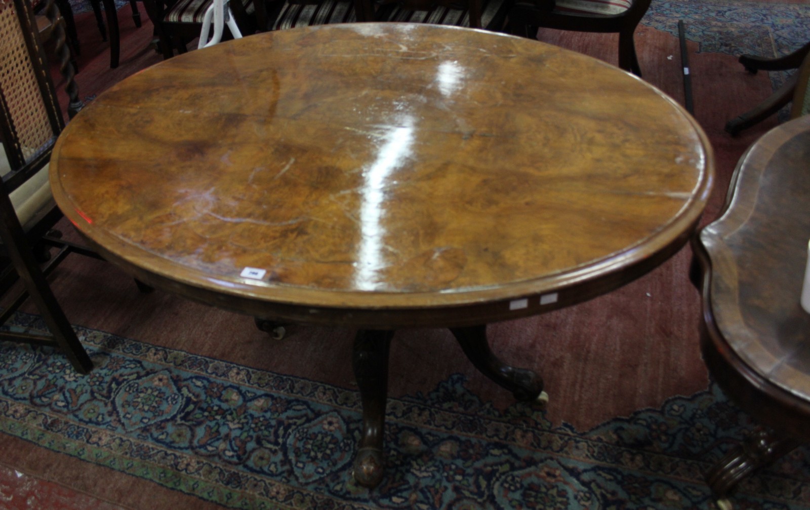 *A Victorian burr walnut oval table on turned column and floral carved legs 135cm wideBest Bid