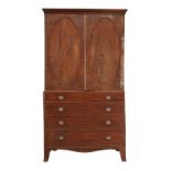 A Regency mahogany linen press, circa 1815, the moulded cornice above twin oval panelled doors, with