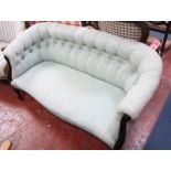 A late Victorian curved button back sofa in pale green damask raised on cabriole front supports.