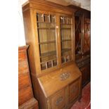A 20th Century oak bureau bookcase, with a glazed upper section and carved fall front and panelled