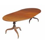 A mahogany two pillar dining table, the oval top with two loose leaves on two turned supports,