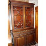 A George III style mahogany bookcase with shelves and cupboard, the upper section with astragal