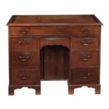 A George II mahogany kneehole desk circa 1740 with a rectangular top, six short drawers flanking a