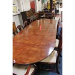 A Georgian style mahogany dining table with two extension leaves raised on two column swept