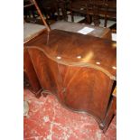 A Georgian style mahogany serpentine fronted cabinet, 20th century, the panel doors enclosing single