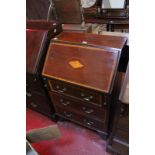 An Edwardian mahogany and inlaid bureau, of small proportions, the fall flap above three long