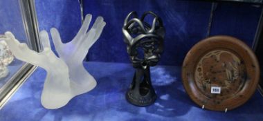 A modern glass sculpture of two hands, a ceramic sculpture of faces marked to the base 'Leon Marais'