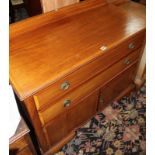 A 20th century chest of drawers with two long drawers above a cupboard doors enclosing a cabinet,